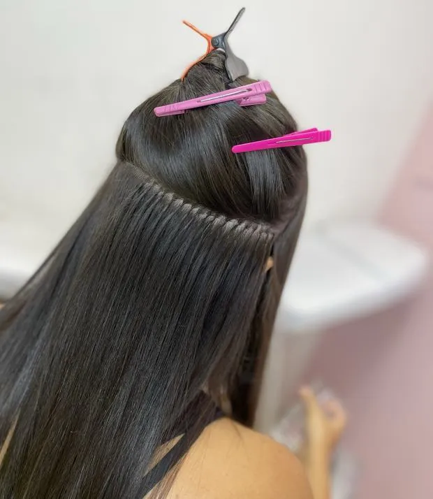 Nuca com a tela costurada presa rente ao couro cabeludo, o cabelo de cima preso com presilhas.